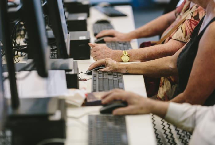 Photo of people's hands typing on the computer keyboard and using the mouse